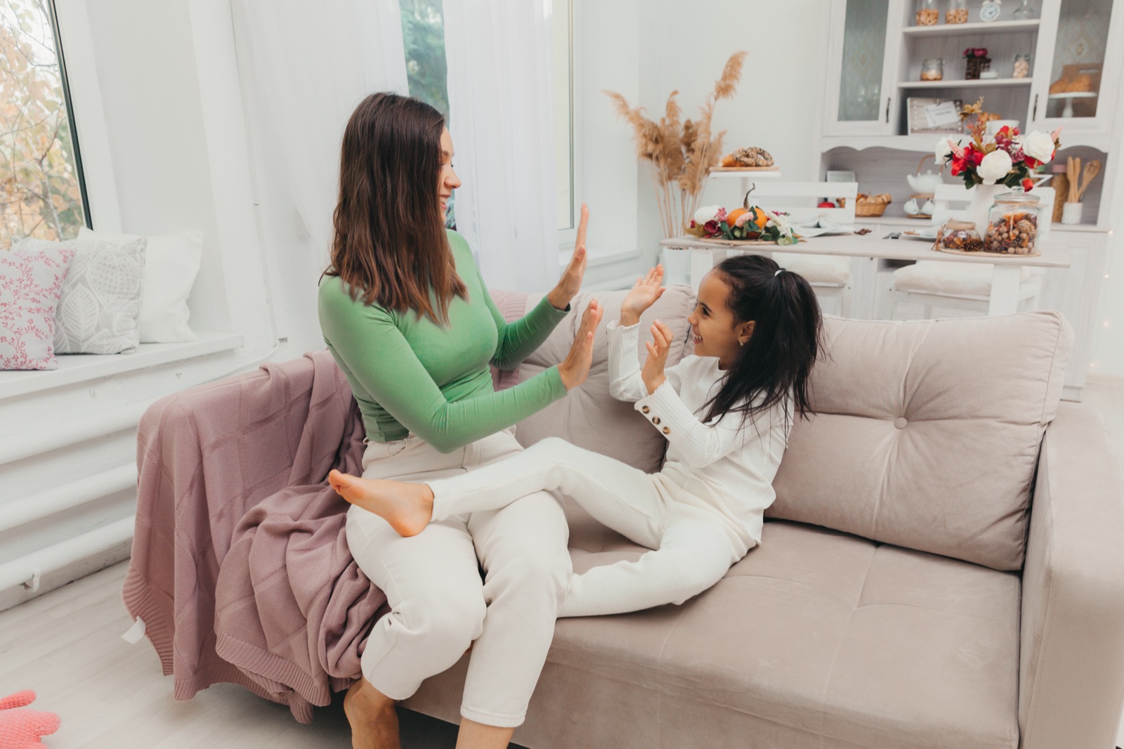 A mother and daughter sharing a joyful high-five at home