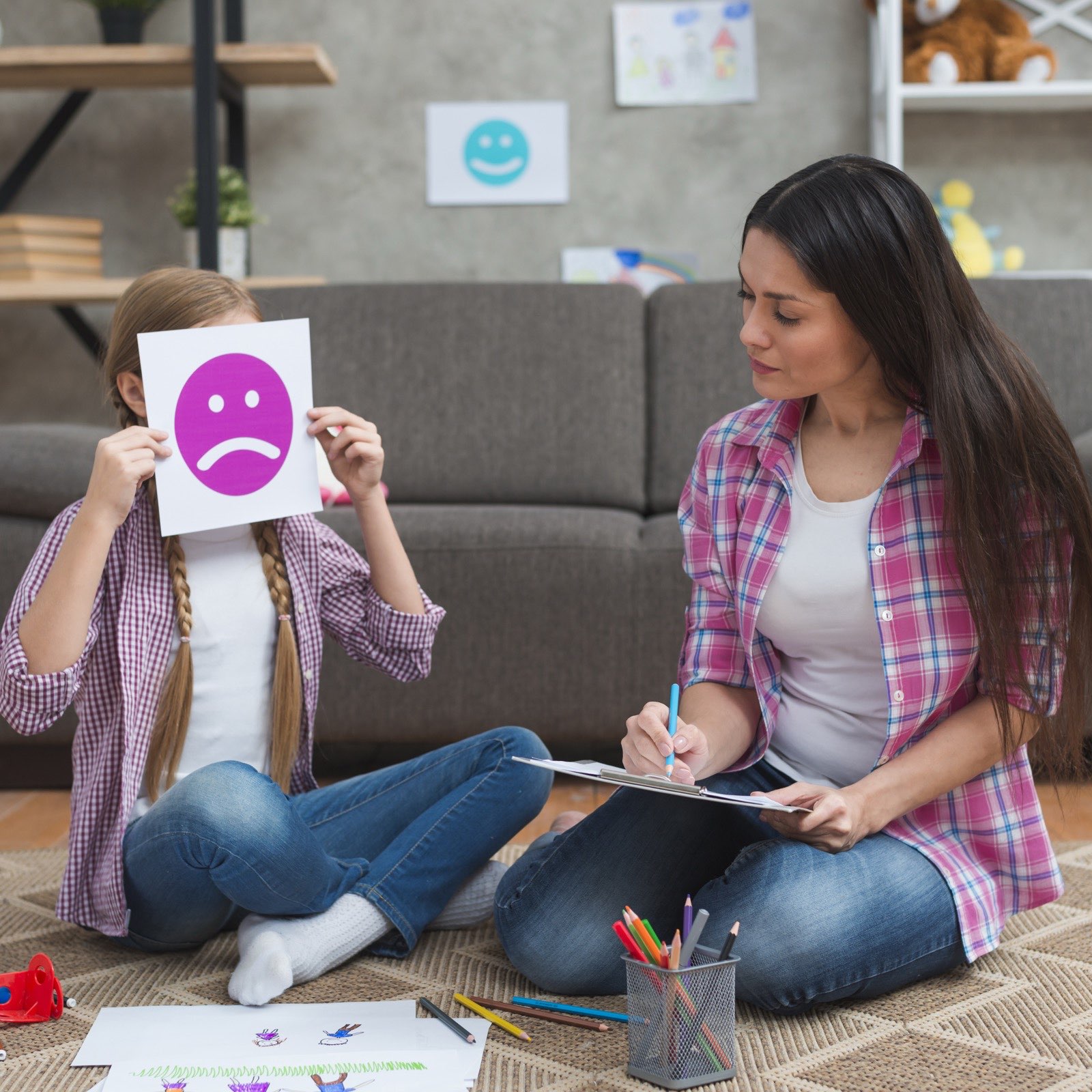 A psychologist taking notes with a girl using an emotion card