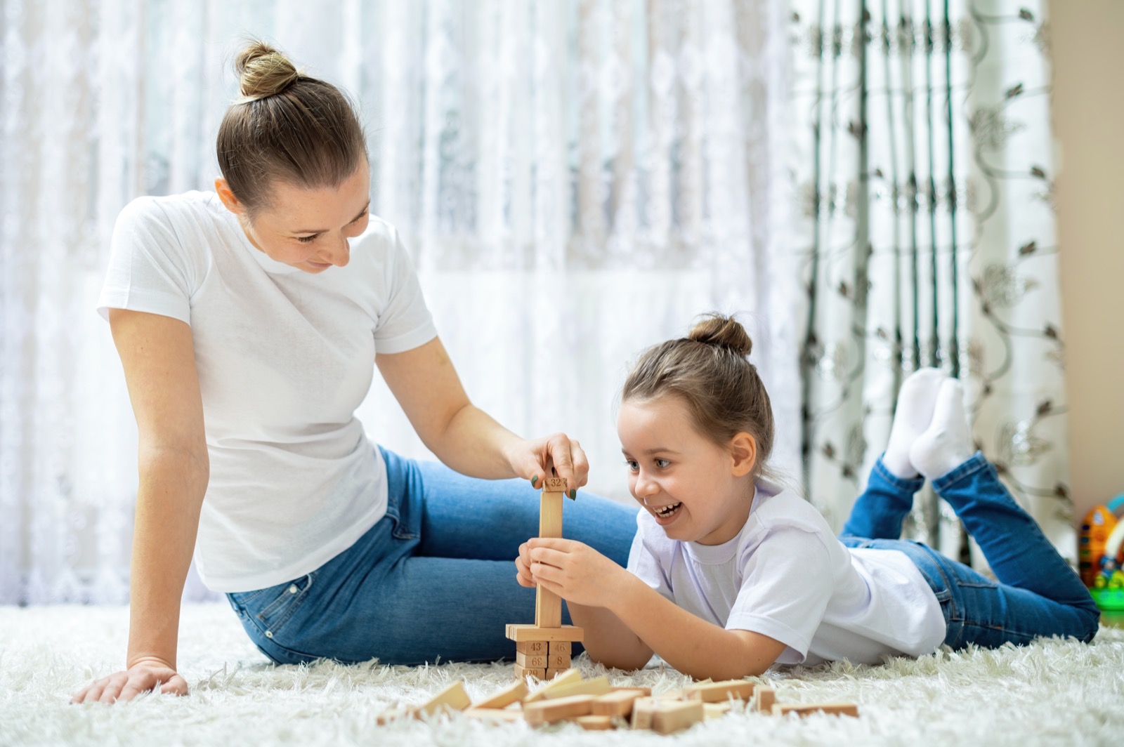 A mother and daughter playing together on the floor at home