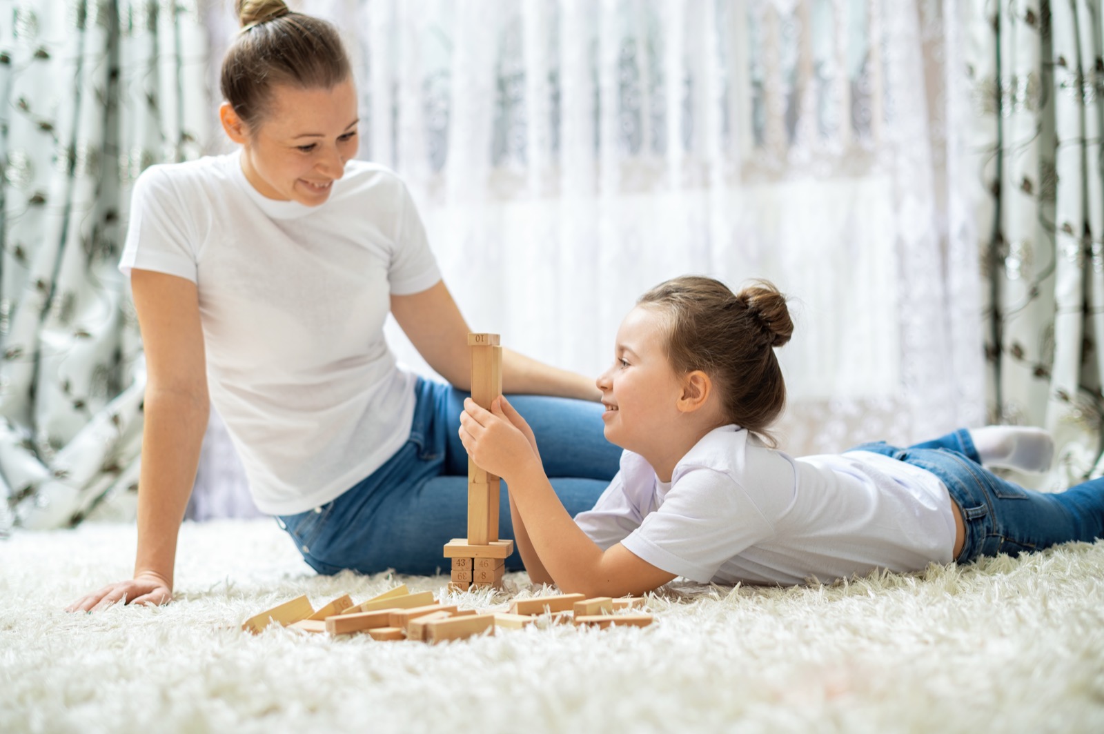 A mother and daughter playing together on the floor at home