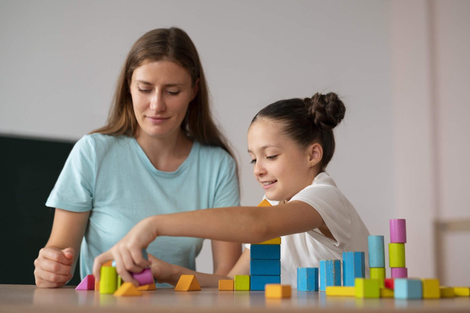 A psychologist helping a girl in speech therapy