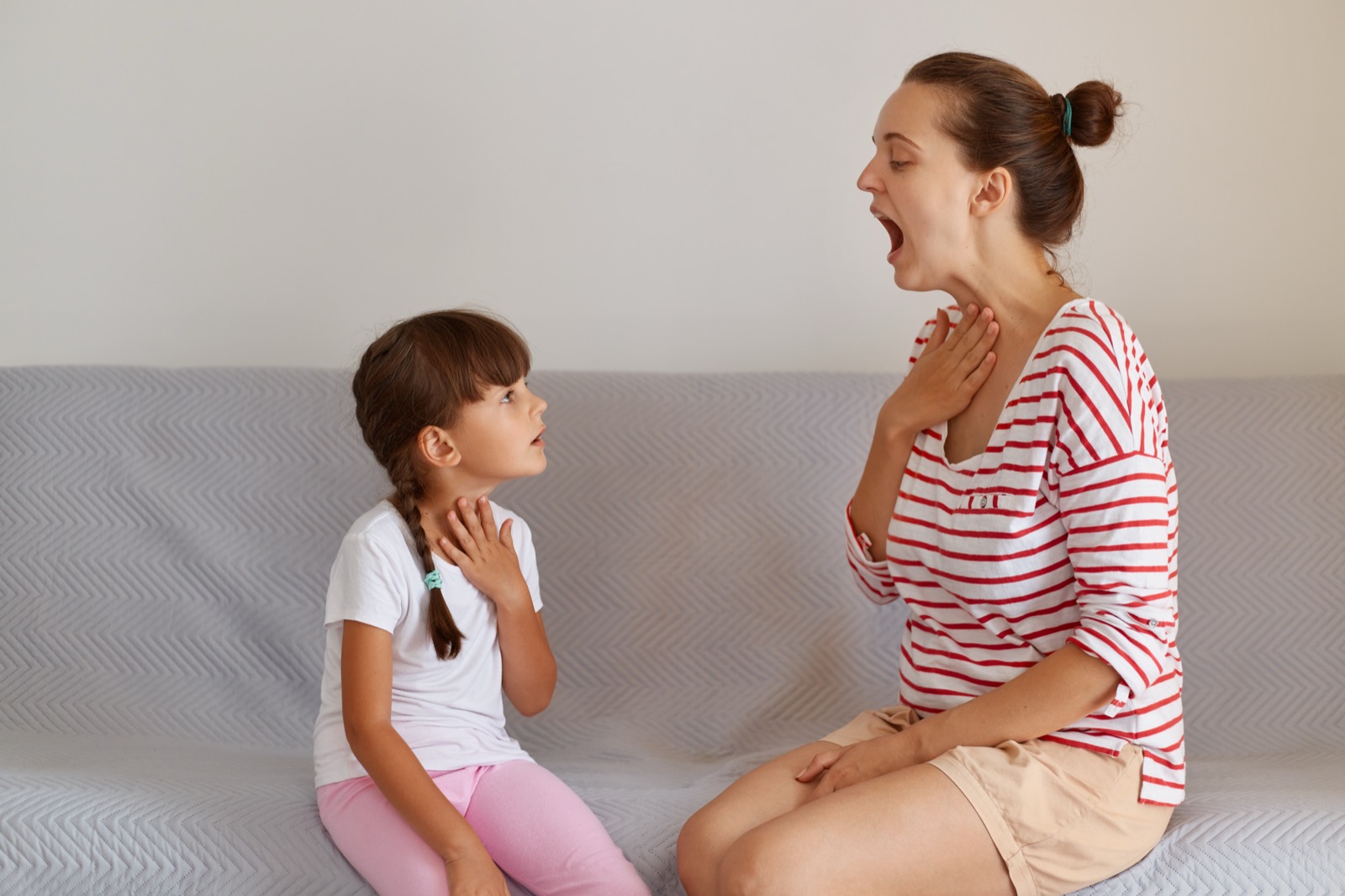 A speech pathologist demonstrating a sound for a child