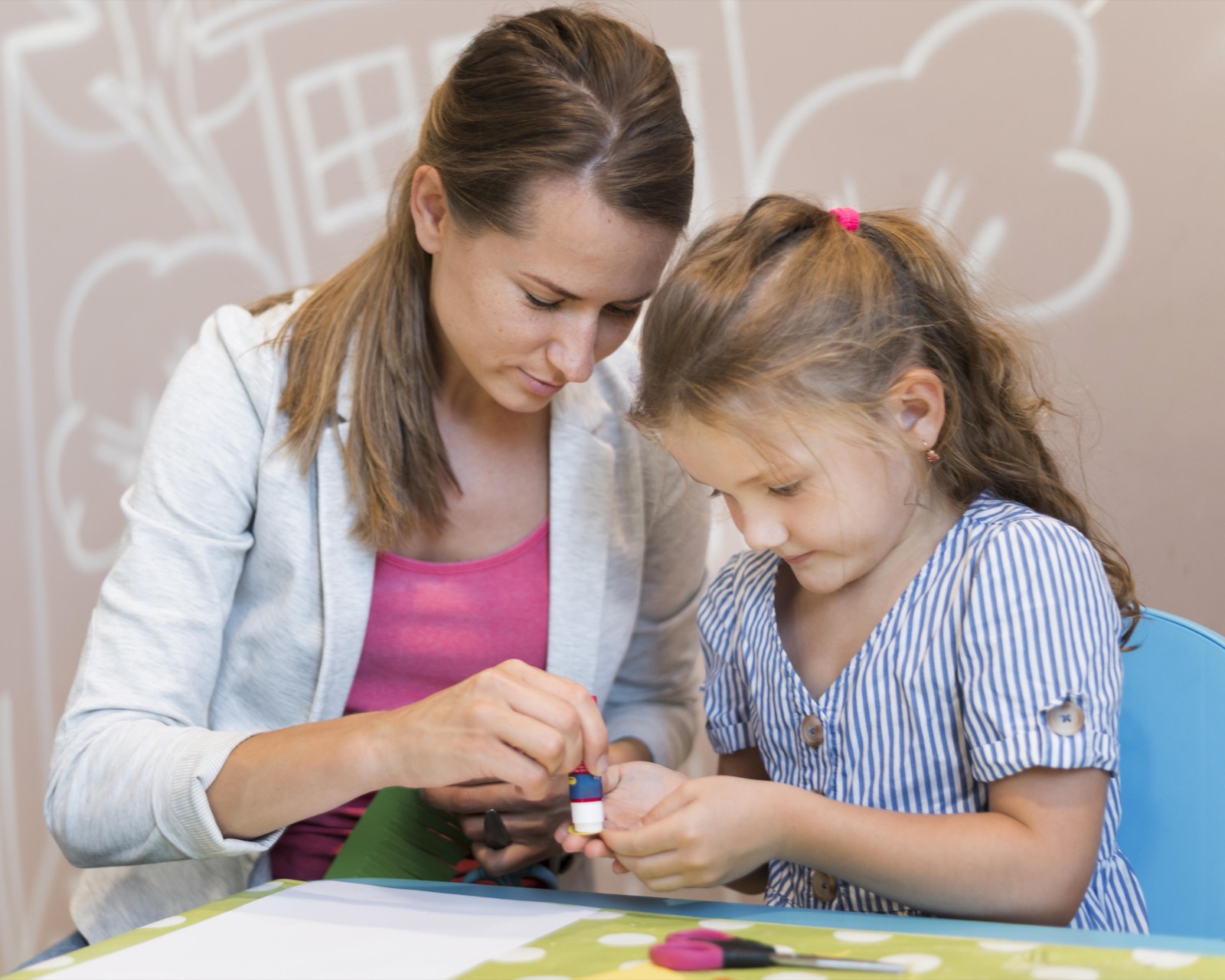 A teacher and a girl gluing paper together