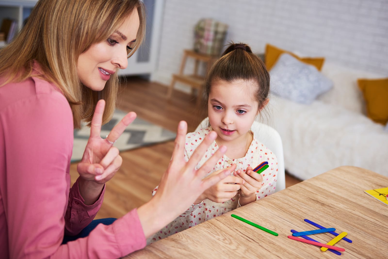 An ABA therapist working with a young girl at a table