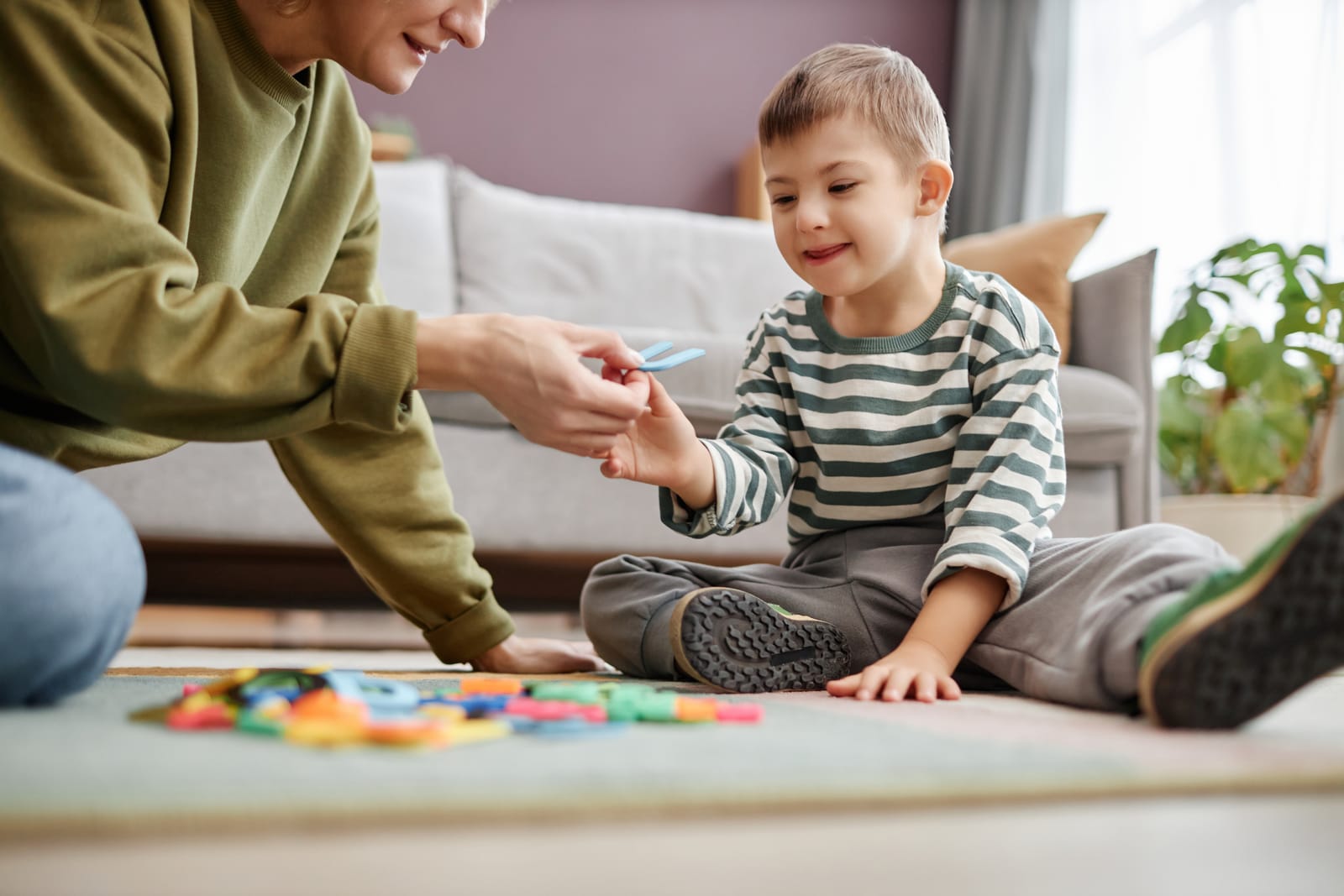 An ABA therapist playing with letter toys with a young boy at home