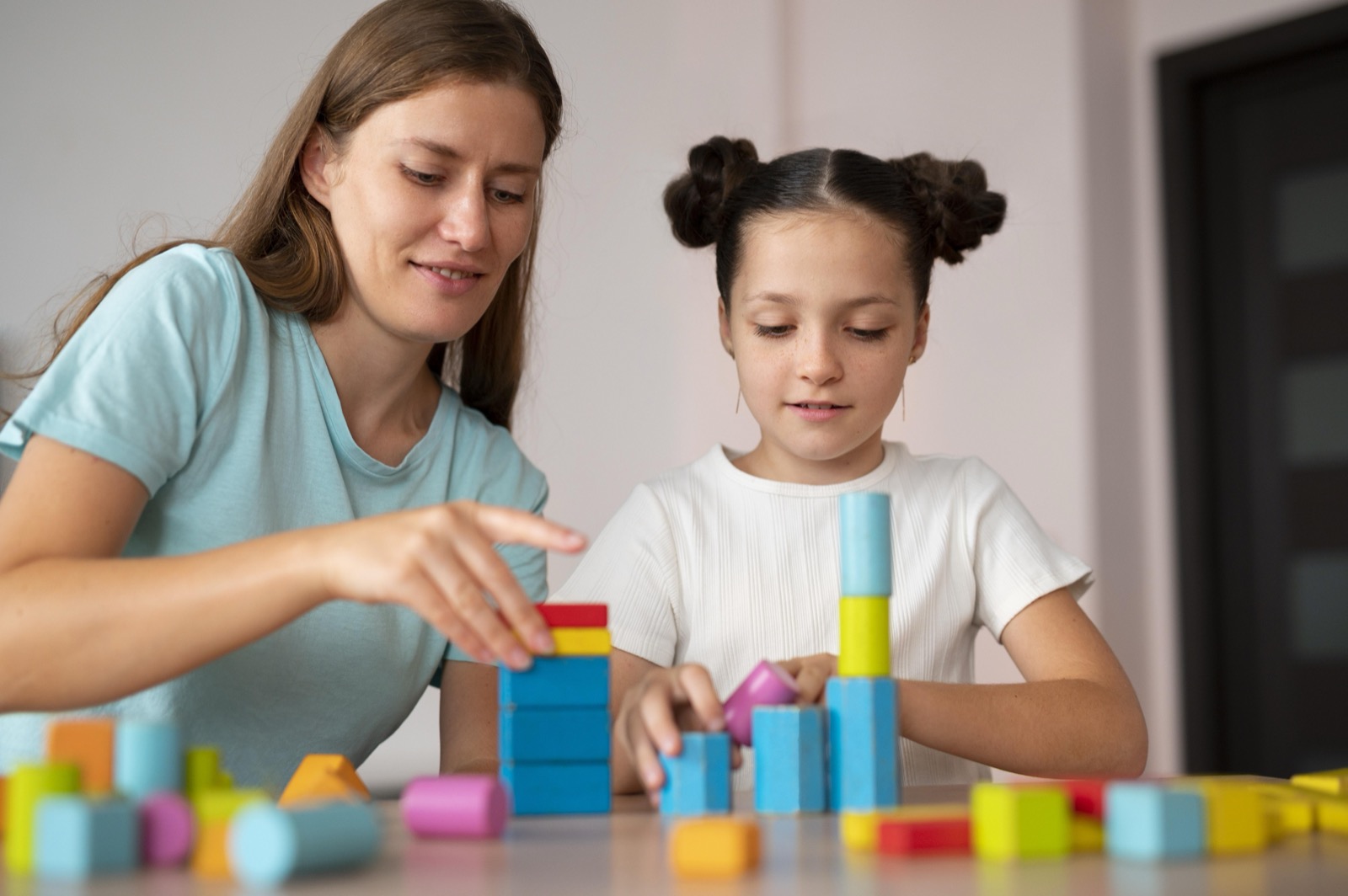 A young psychologist helping a girl in speech therapy