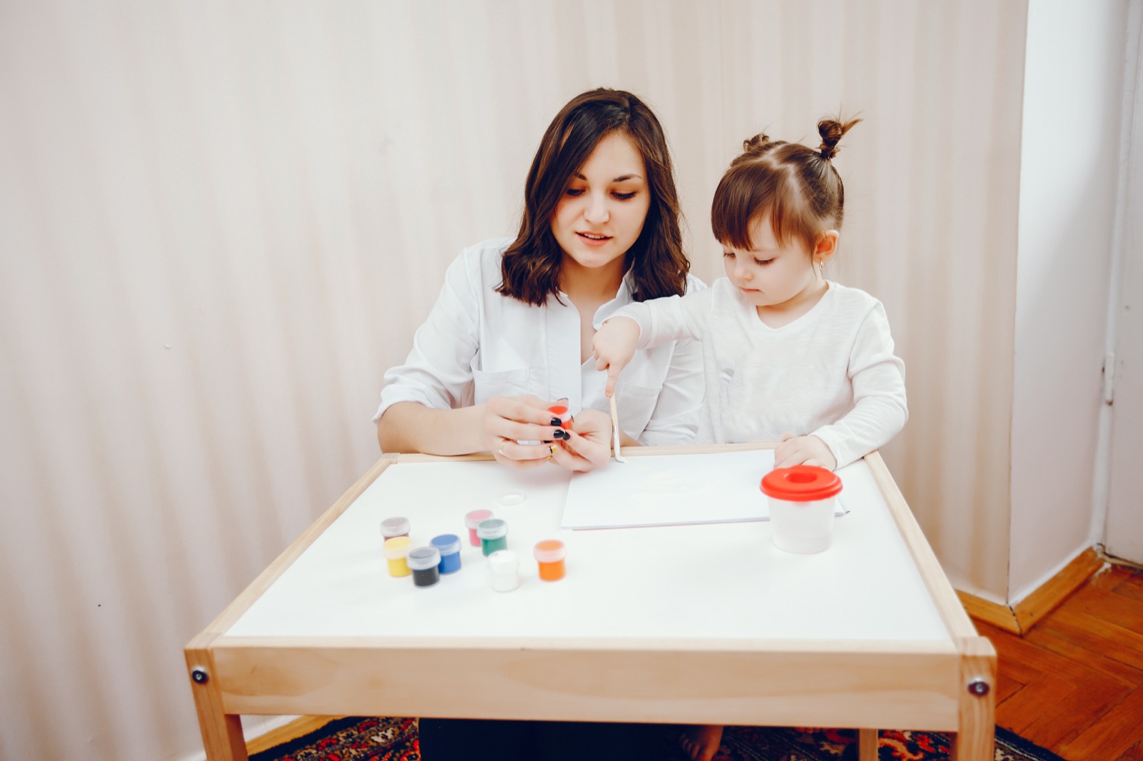 A mother and her daughter painting on paper