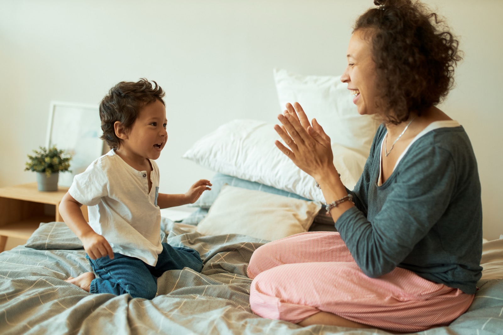 A mother seated on a bed with her young son