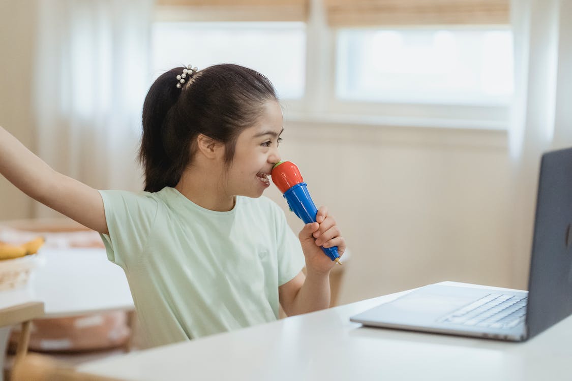 Free A Young Girl Singing while Looking at Laptop Stock Photo