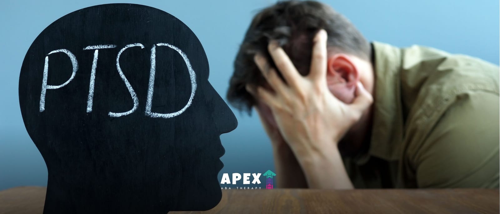 A distressed man clutches his head beside a black profile silhouette labeled “PTSD,” conveying trauma, anxiety, and emotional struggle.