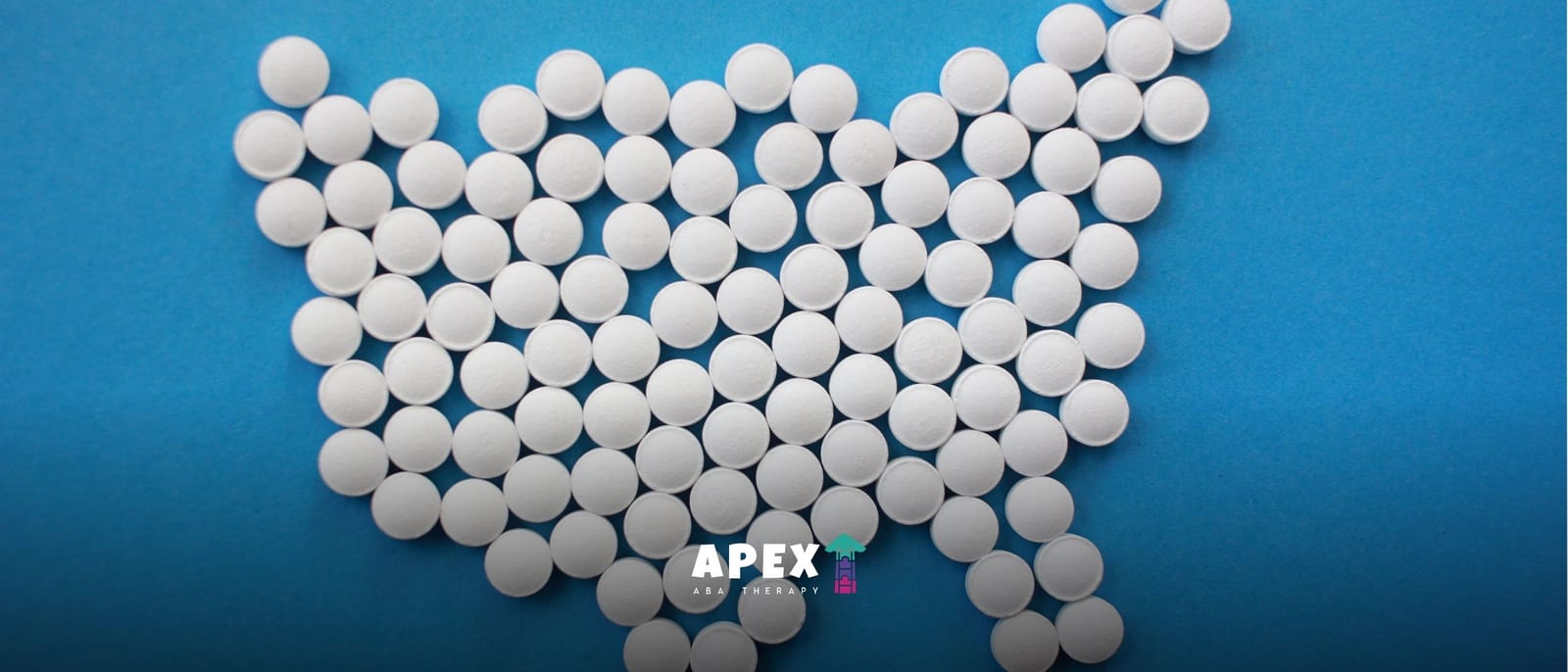 White round tablets form the shape of a heart on a bright blue surface, with a small APEX logo below; the overhead image feels clean and clinical.