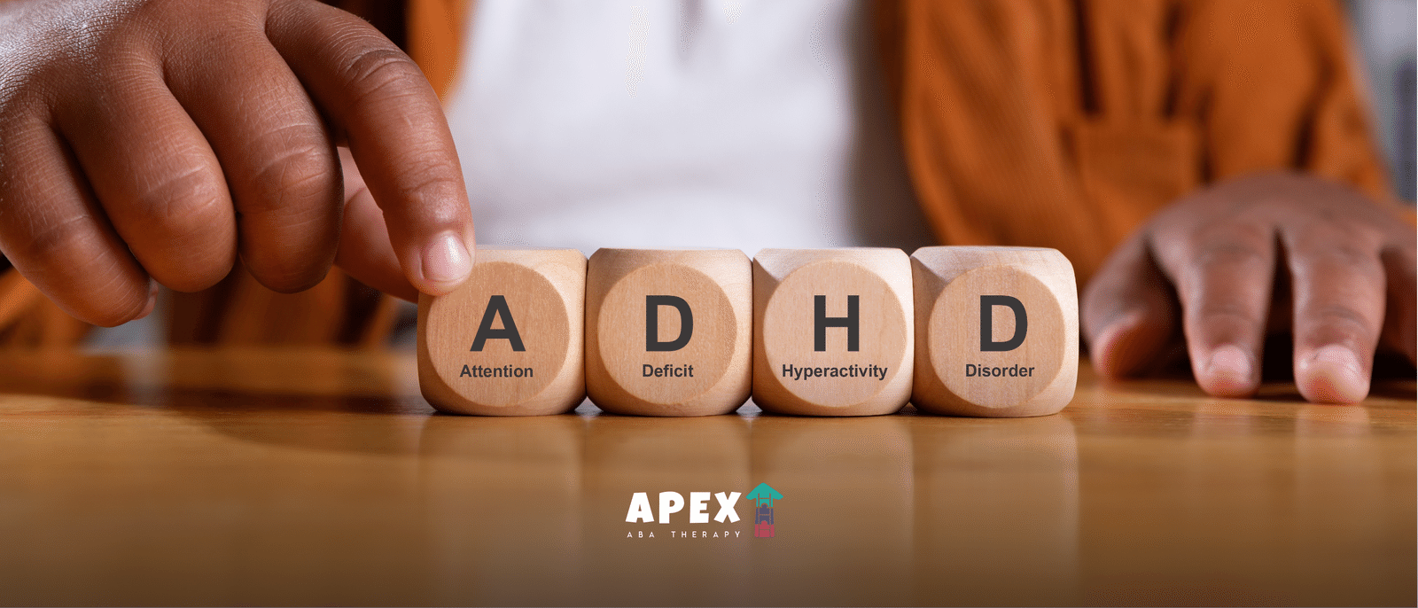 Wooden blocks spelling ADHD, with the words Attention Deficit Hyperactivity Disorder printed beneath each letter, arranged on a table.